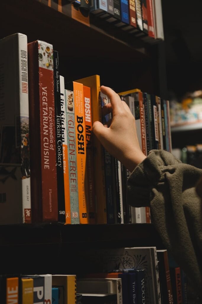 Close-up of hand reaching for a book in a library in Ankara, Türkiye.
